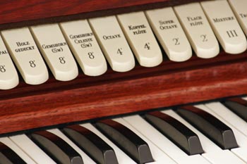 A closeup of an organ keyboard and stops