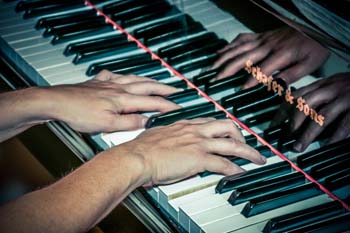 Hands on piano keys with reflective piano